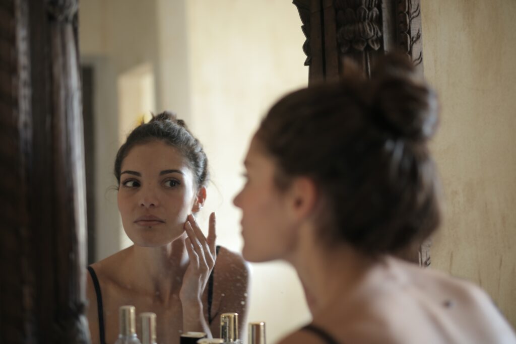 woman studying her skin in mirror