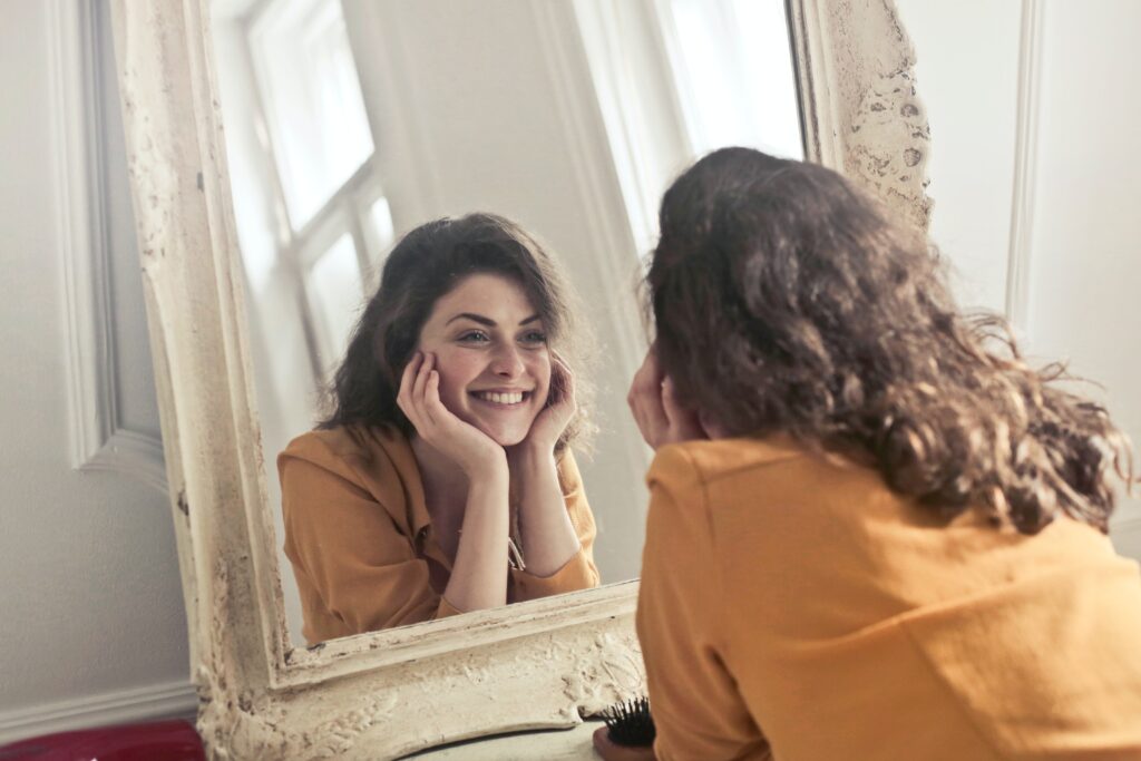 woman with healthy skin smiling in mirror