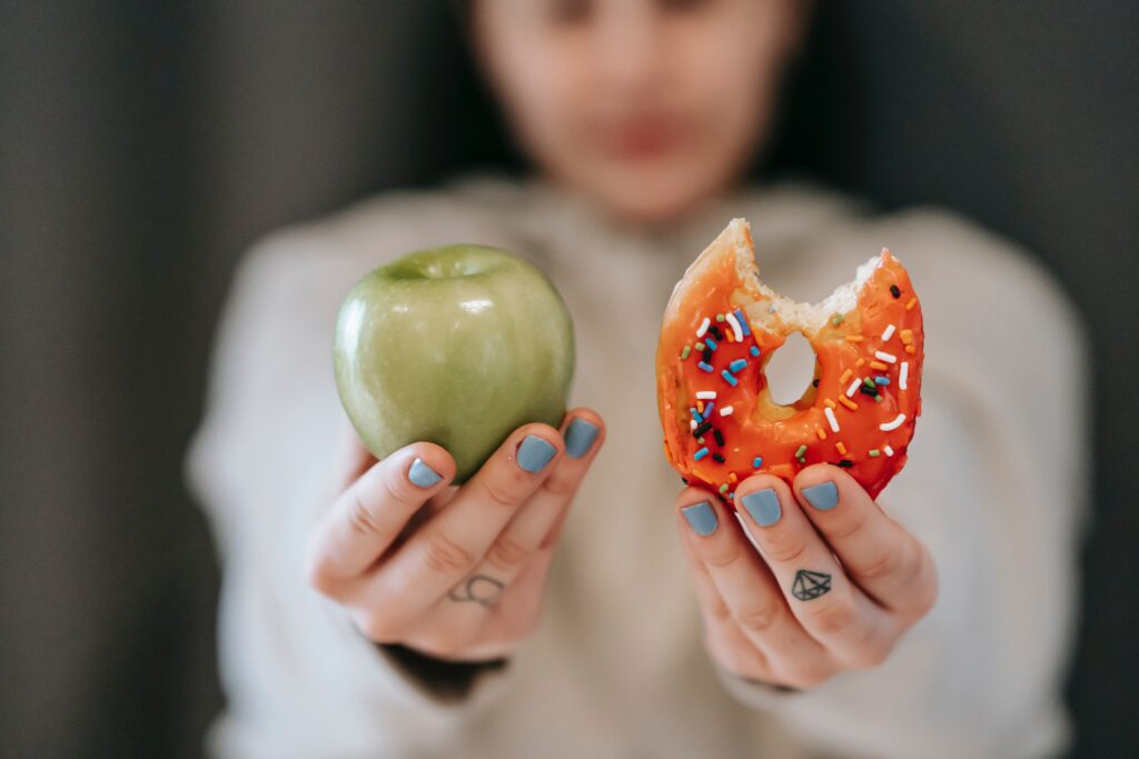 Image of woman holding an apple and a donut
